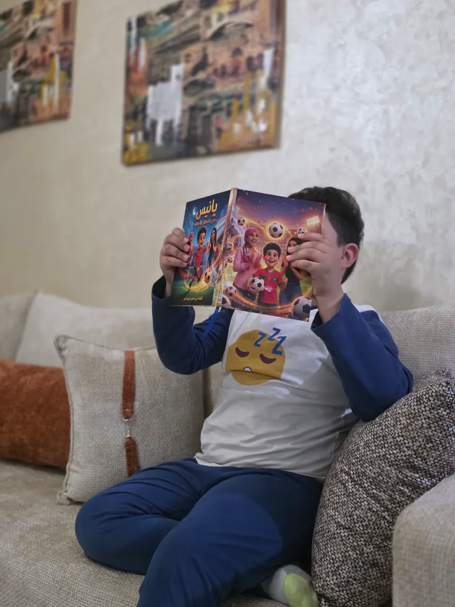 طفل يختبئ خلف كتابه المخصّص