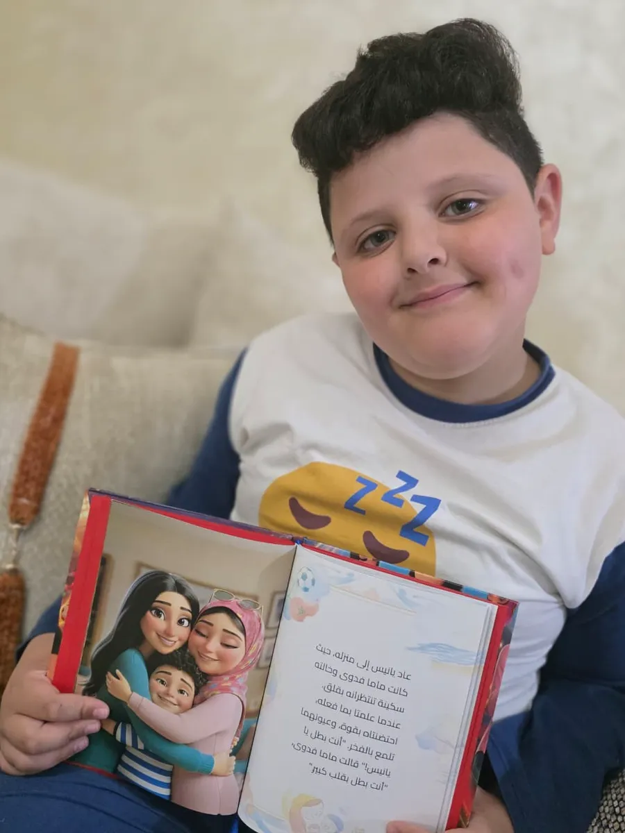 نفس الطفل يُري صفحة من كتابه بالعربية